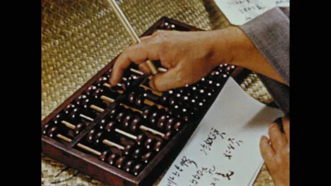 1950s: Hand counting on abacus. Tracking shot of men working at desks. Aerial Stock Footage 130357976