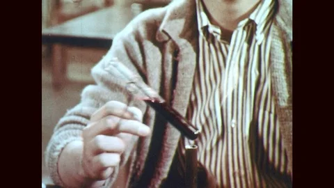 1950s: Hand holds test tube over flame. Boy in lab heats test tube, turns and Stock Footage