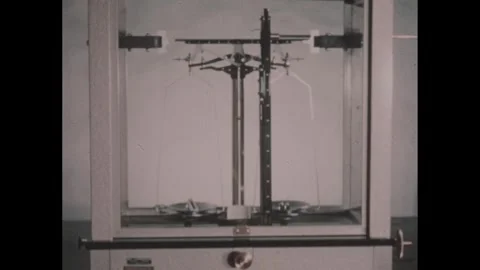 1950s: Hand points to balance scale in chamber. Video stock 254443821