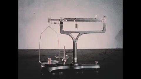 1950s: Hand points to copper weight on balance scale. Stock Footage 303660451
