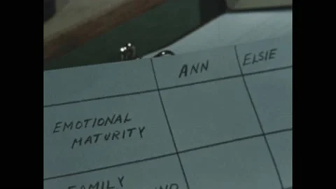 1950s: Hands hold comparison chart. Man snaps clapper in hallway. Boy exits Stock Footage 189954234