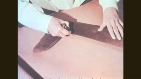 1950s: Hands use tools to trace pattern on leather. Man works at workbench. Stock Footage 78042853