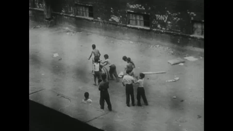 1950s: High angle shot, kids playing in alley / Boy hops down from window. Stock Footage