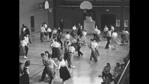 1950s: High school.  Students square dance in gym.  Men look at car at gas 動画素材 253832100