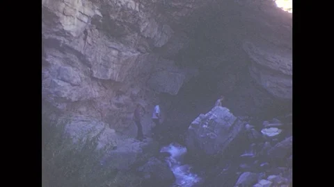 1950s: Hikers On Boulders At Bottom Of Waterfall. Sign For Rick's Springs. Older Stock Footage