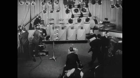 1950s: Interior set in television studio. Cameras move into position. Orchestra Stock Footage 162327022