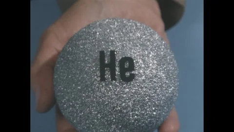 1950s: letters "He" on gray background, hand holds gray styrofoam ball with "He" Stock Footage 279488541