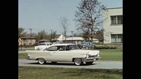 1950s: Low angle, car drives past camera. Pan of car driving. Train engine Stock Footage 146798018