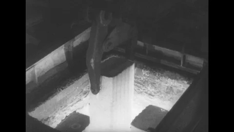 1950s: Machine lifts object, Men operate equipment, Hot object runs down belts Stock Footage