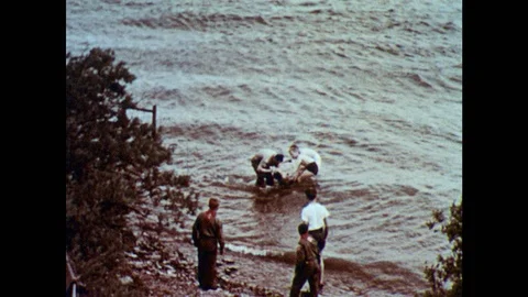 1950s: Man and boys pull drowning victim from water.  Man pushes on boy's Stock Footage 97555101
