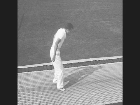 1950s: Man bounces on trampoline, landing on his backside, knees, stomach, and Stock Footage