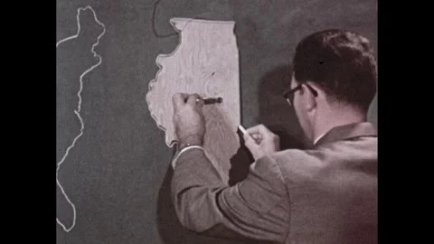 1950s: Man holds stencil of map by handle as he draws outline of map on Vidéo 253832999