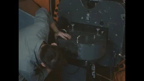 1950s: Man inserts component into cyclotron and adjusts knobs. 스톡 동영상 286713933