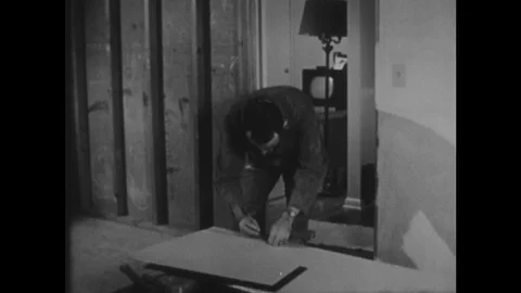 1950s: Man inside house makes measurements on piece of sheetrock. Man uses Stock Footage 116052873