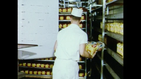 1950s: Man loads packages of bread onto delivery truck. Loaves of bread emerge Stock Footage 91707213