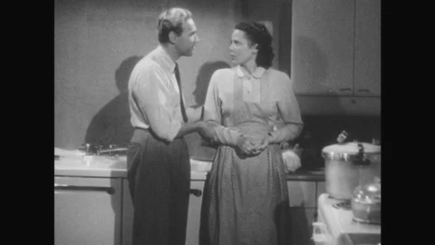 1950s: man in necktie and woman in apron talk, cry, put objects in sink and cook Stock Footage