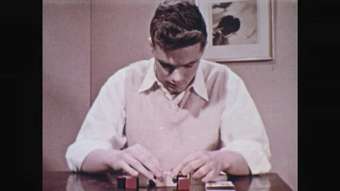 1950s: Man places blocks of cubes on table. Hand pushes needle on multiple Stock Footage 77740047