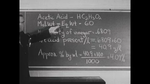 1950s: Man pointing at and explaining the information about acetic acid. Stock Footage 241509014