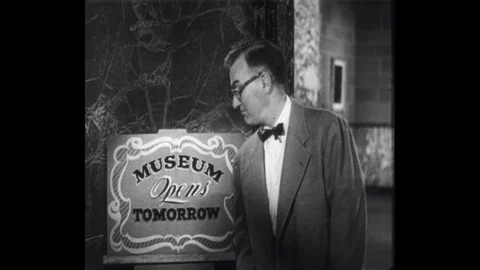 1950s: Man points to sign, tracking shot, man walks to torch, talks into camera. Stock Footage 112497766