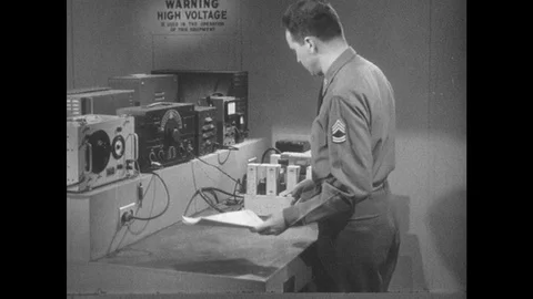 1950s: Man positions electronics on table. Man turns band selector switch on Video stock 89858283
