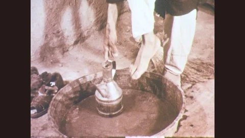 1950s: Man pours water on foot. Man scrubs. Man stands and adjusts keffiyeh. Stock Footage