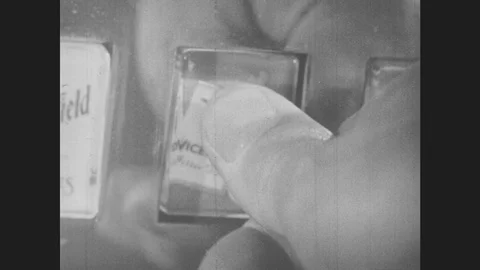 1950s: A man presses a button on a cigarette vending machine and takes his pack. Видео 86230141