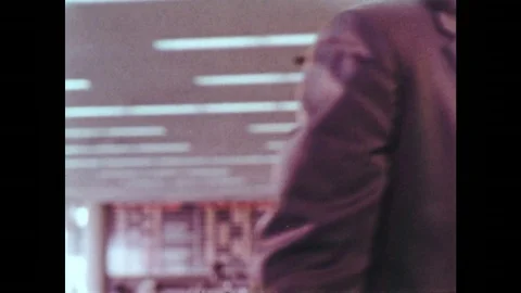 1950s: Man presses buttons on machine. Children watch suitcases on conveyor belt Stock Footage