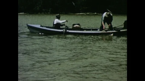 1950s: Man pulls drift nets from water in rowboat. Man removes fish caught in Stock Footage 103555605