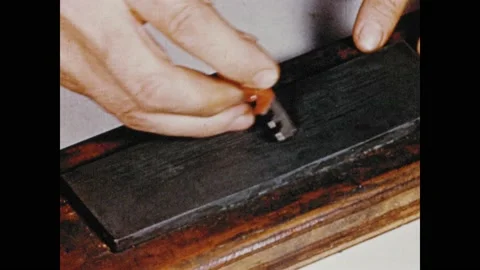 1950s:  Man sharpens tool.  Man uses tool to trace around pattern piece on Stock Footage 134354170