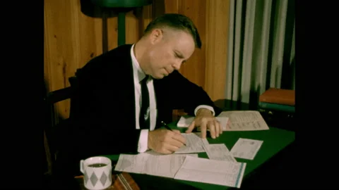1950s: Man sits at desk filling out tax forms. Stock Footage