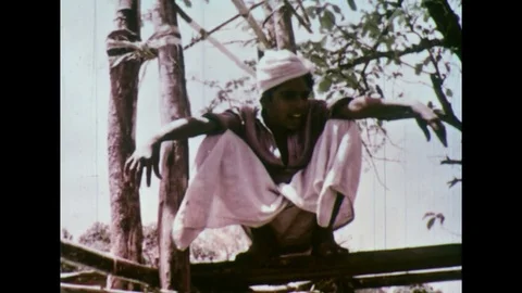 1950s: Man squatting / Men pull ropes / Wood lifted off of elephant / Elephant Stock Footage 74628206