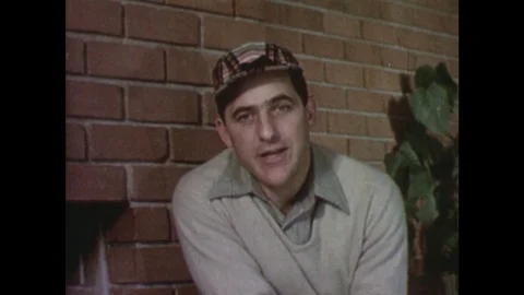 1950s: man talks direct to camera and smiles and laughs. Feet walk along path. Stock Footage