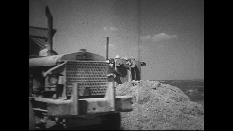 1950s:A man on a tractor pushes a large pile of dirt. Stock Footage