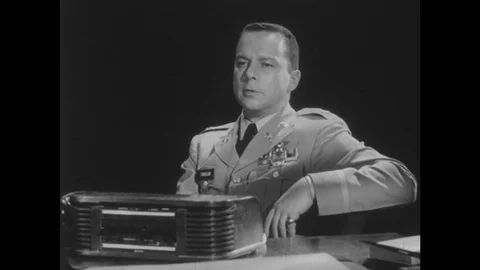 1950s: Man in uniform sits in chair, talks, and leans forward. Man in uniform Stock Footage