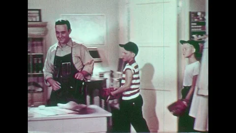 1950s: Man walks through door places camera on table. Boys follow. Boys outside Stock Footage