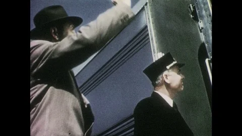 1950s: Man waves goodbye to train car. Train engineer leans from window and Stock Footage 83944169