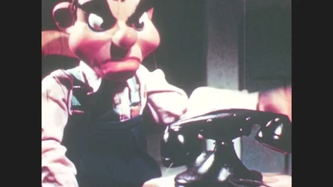 1950s: Marionette man puppet sets phone receiver down on cradle, looks at Stock Footage 79474878