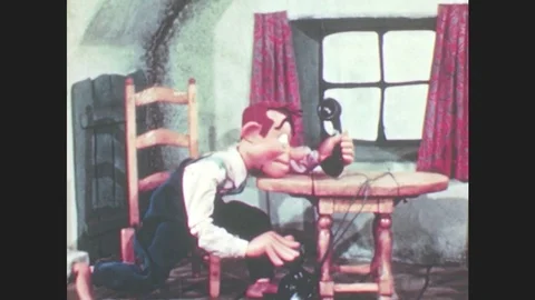 1950s: Marionette man puppet sits at table, looks grumpily at telephone. Puppet Stock Footage 79474893