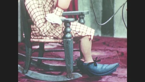 1950s: Marionette puppet sits in rocking chair, taps feet. Puppet looks at Stock Footage 79474875
