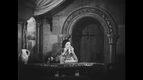 1950s: Medieval man eats in a stone castle. Reader entertains a medieval court Stock Footage 128006727