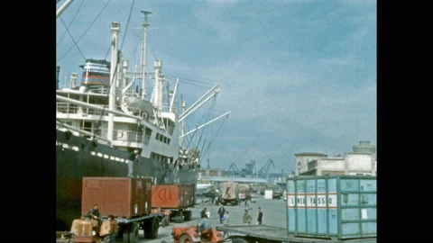 1950s: Men and crane load crates onto cargo ship at docks. Women watch fashion Stock Footage 139760209