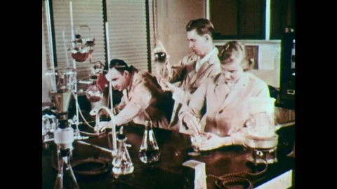 1950s: Men and woman work in lab mixing liquids. Mechanical liquid mixer at Stock Footage