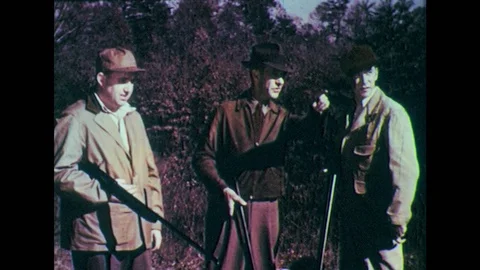 1950s: Men arguing in forest, holding guns. Man leans on gun barrel. Stock Footage