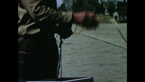 1950s: Men cast drift nets from small rowboat onto river. Stock Footage 103555600
