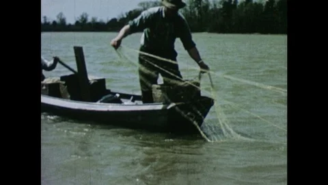 1950s: Men cast drift nets from small rowboat onto river. Stock Footage 103555602