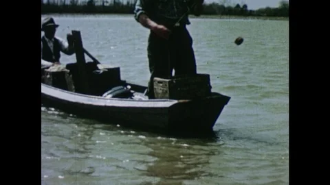 1950s: Men cast drift nets from small rowboat onto river. Cork floats drift on Stock Footage 103555603