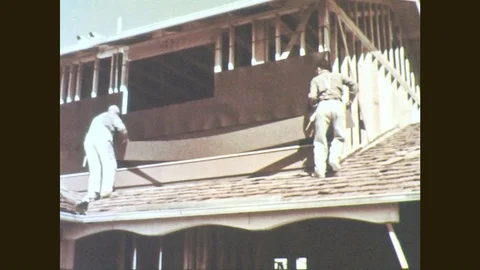 1950s: Men fasten sheets to building. Man applies wet building material to mesh Stock Footage