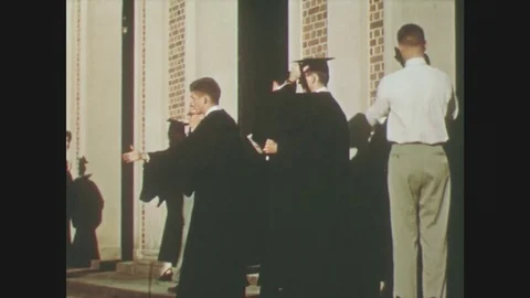 1950s: men in graduation gowns shake hands with men and women. band plays on Stock Footage