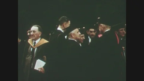 1950s: men in graduation gowns talk. sun sets behind belltower. men and women Stock Footage