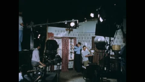 1950s: Men hold clapper and adjust lights on film production set. Labeled water Stock Footage 169593611